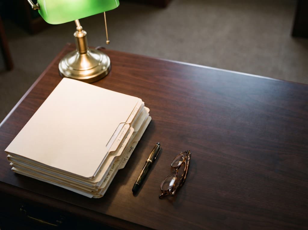 A veteran's legal case file under a banker's lamp